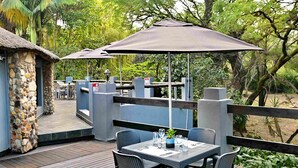 A patio with outdoor seating, a stone building, and a thatched-roof structure. - BON Hotel Rustenburg (Rustenburg)