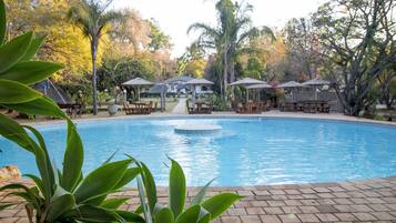 Una piscina cubierta, una piscina al aire libre, sombrillas, tumbonas