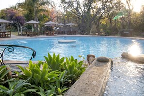 Una piscina techada, una piscina al aire libre, sombrillas