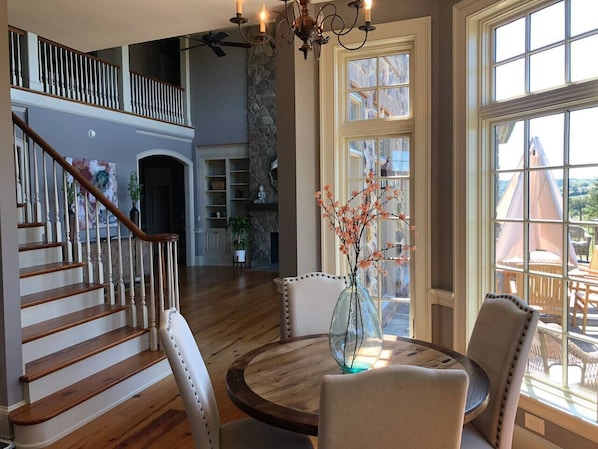 Stunning interior with a grand staircase, round table, and fireplace, offering a view of the outdoors.