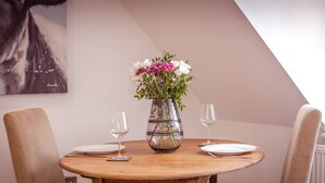 Ein runder Holztisch mit zwei Stühlen, einer Blumenvase und zwei Weingläsern.