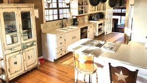 A rustic kitchen with a wooden island, white cabinetry, and hanging pots. - 4 Maples on the Frio, Riverfront, Wi-Fi, @ Frio River Vacation Rentals (Concan)