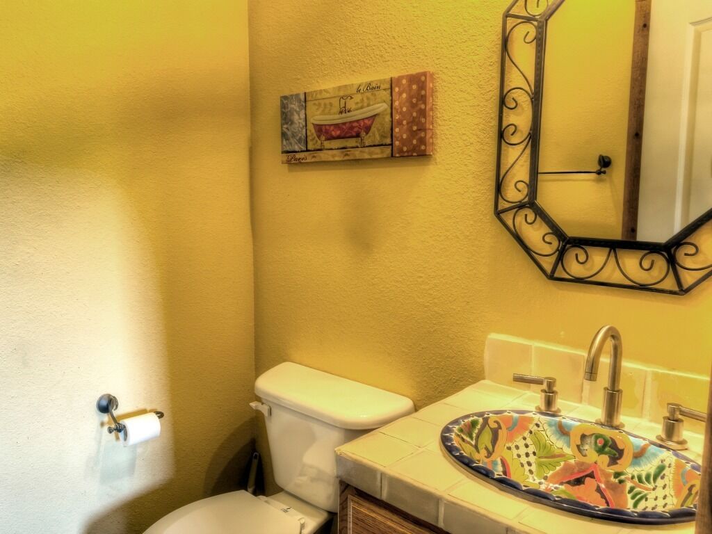 A bathroom with a toilet, sink, and mirror.