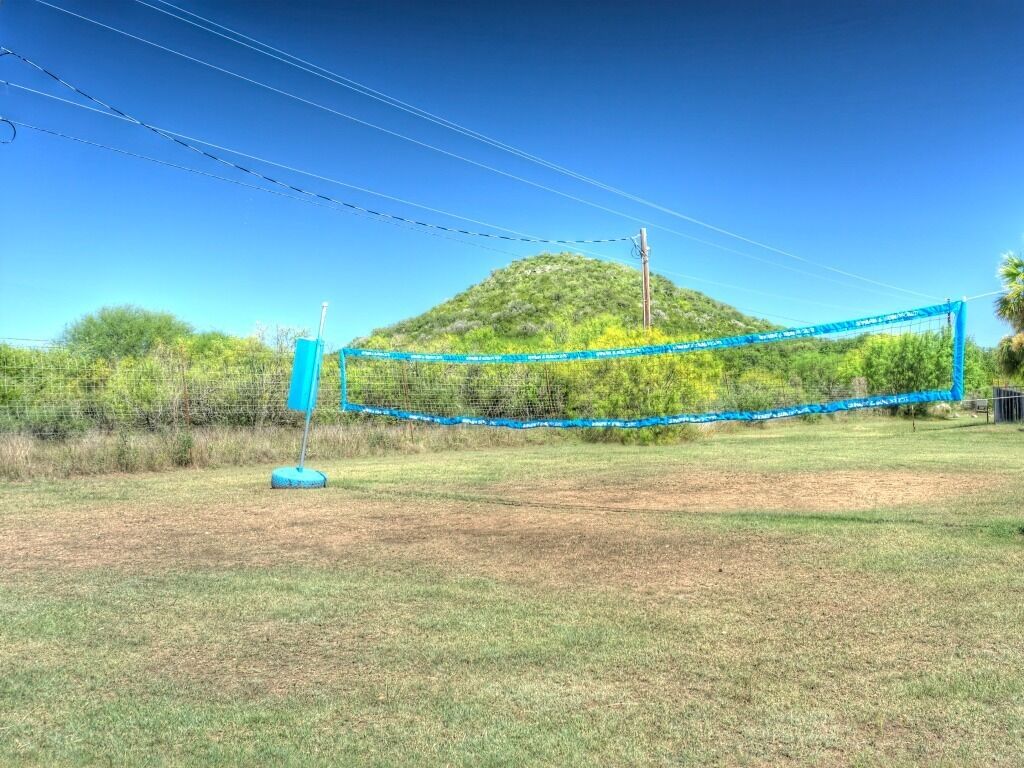 A volleyball net in an open field with a hill in the background.