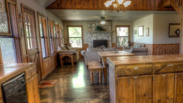 A spacious kitchen with wooden cabinets, a central island, and a stone fireplace. - Casa del Sol, Private Pool, Wi-Fi, @ Frio River Vacation Rentals (Concan)