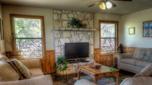 A cozy living room with a stone fireplace, wooden furniture, and a flat-screen TV. - Casa del Sol, Private Pool, Wi-Fi, @ Frio River Vacation Rentals (Concan)