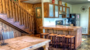 A rustic kitchen with wooden cabinets, a wooden bar counter, and stools. - Casa del Sol, Private Pool, Wi-Fi, @ Frio River Vacation Rentals (Concan)