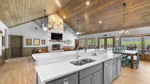 A spacious kitchen with a large island, built-in appliances, and a stone fireplace. - Celebration Station, Private Pool, Wi-Fi, @ Frio River Vacation Rentals (Concan)