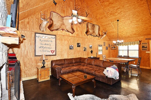 A cozy living room with a brown leather sectional sofa, a wooden coffee table, and a fireplace.