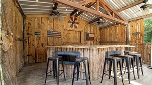 A rustic wooden bar area with a ceiling fan, a clock, and a sign indicating a restroom. - Stone Creek, Private Pool, Wi-Fi, @ Frio River Vacation Rentals (Concan)