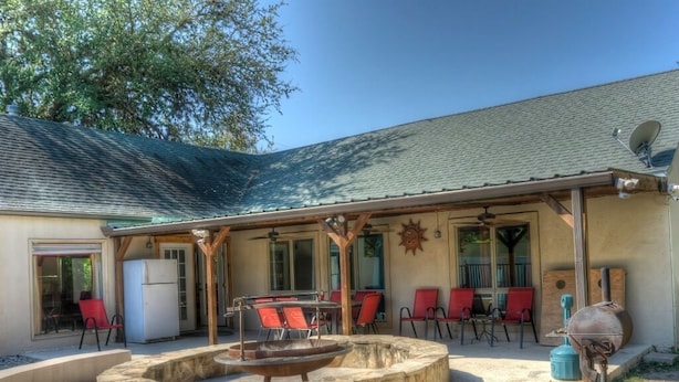 An outdoor patio with a stone fire pit, red chairs, and a barbecue grill. - Stone Creek, Private Pool, Wi-Fi, @ Frio River Vacation Rentals (Concan)