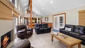 A spacious living room with leather sofas, a wooden coffee table, and a fireplace. - Stone Creek, Private Pool, Wi-Fi, @ Frio River Vacation Rentals (Concan)