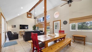 A spacious living area with a wooden dining table, red chairs, a sofa, and a ceiling fan. - Stone Creek, Private Pool, Wi-Fi, @ Frio River Vacation Rentals (Concan)