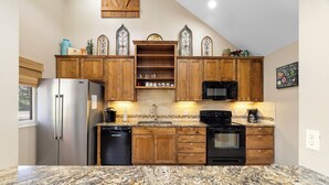 A kitchen with wooden cabinets, a stainless steel refrigerator, a microwave, and a stove. - Stone Creek, Private Pool, Wi-Fi, @ Frio River Vacation Rentals (Concan)