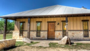 A rustic building with a stone facade, a wooden door, and a metal roof. - Rustic Tavern @ Frio River Vacation Rentals (Concan)