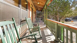 Eine überdachte Veranda mit grünen Stühlen und einem Holzbalkon.