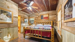 Ein rustikaler Holzraum mit einem Bett, einem Deckenventilator und gerahmten Bildern an den Wänden.