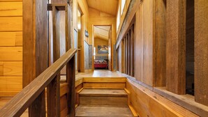 A wooden staircase in a log cabin interior with a view of a bedroom at the top. - Coyote Canyon Lodge, Private Pool, @ Frio River Vacation Rentals (Concan)