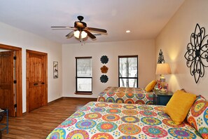 A room with two beds, a ceiling fan, wooden doors, and a wall-mounted lamp.