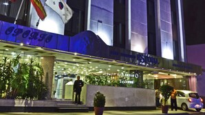 A modern building with a prominent entrance, flags, and a well-lit facade. - Hotel Estoril (Mexico City)