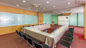 A conference room with a long table, chairs, a projector screen, and a podium. - Hotel Estoril (Mexico City)