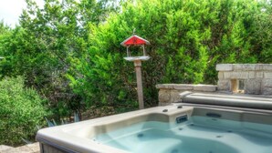 Un bain à remous doté d’une structure en pierre et d’une nichoir dans un jardin.