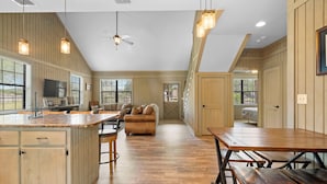 A spacious kitchen with wooden cabinets, a large island, and a dining area with benches. - Firefly @ Frio River Vacation Rentals (Concan)