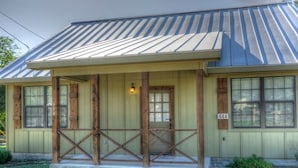 A single-story house with a porch, numbered 664, featuring a metal roof and wooden columns. - Firefly @ Frio River Vacation Rentals (Concan)
