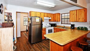Eine Küche mit Holzschränken, einem Edelstahlkühlschrank, einer Mikrowelle und einer Holz Arbeitsplatte.