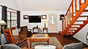 Ein Wohnzimmer mit einer Holztreppe, einem Fernseher und einem Kamin.