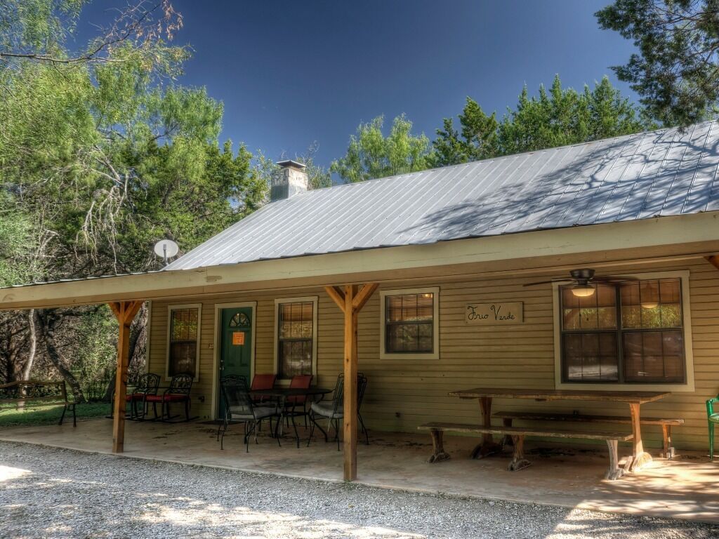 A rustic building with a porch, wooden benches, and a table.