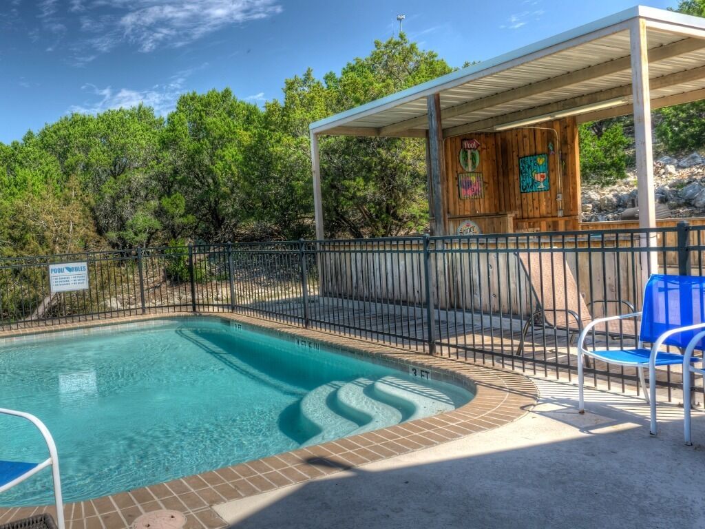 A swimming pool with a wooden deck and a covered seating area.