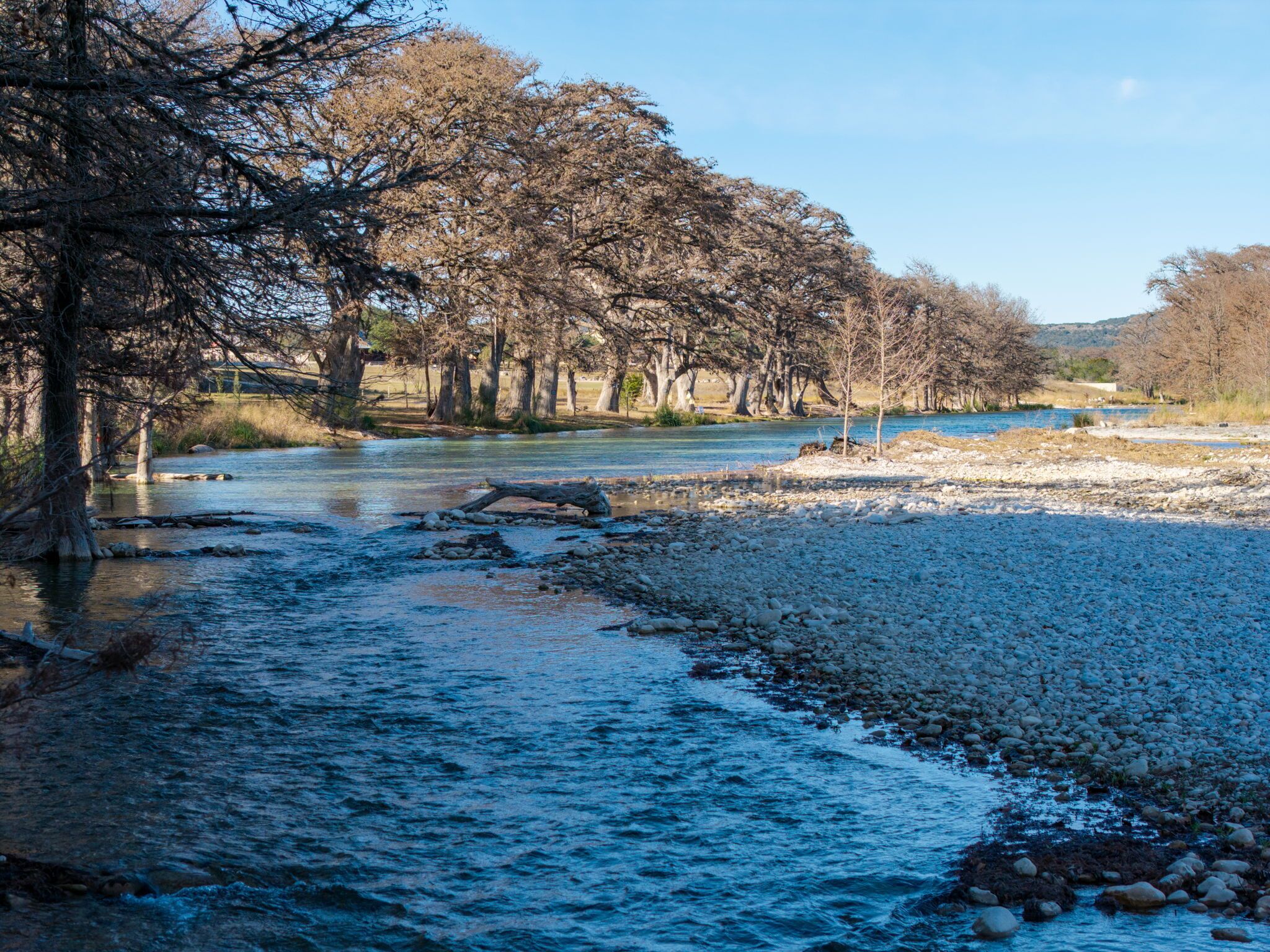 A river with a rocky riverbed and trees lining the banks.