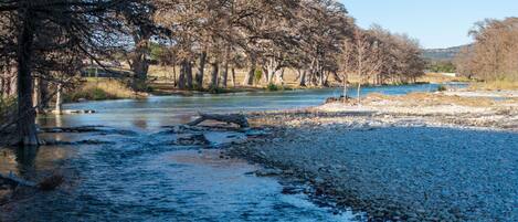 A river with a rocky riverbed and trees lining the banks.