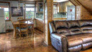 Ein gemütliches Dachzimmer mit Esstisch und Stühlen, einem Ledersofa, Holzschränken und einer Küchenzeile.