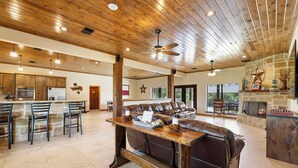 Un salón espacioso con techo de madera, chimenea de piedra y un amplio sofá de cuero.