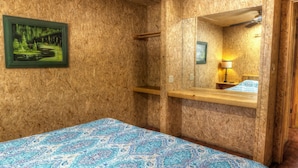 A room with a bed, a wooden shelf, a mirror, a painting, and a lamp. - Not To Worry, Wi-Fi, @ Frio River Vacation Rentals (Concan)