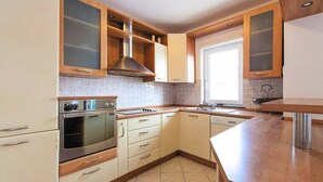 A modern kitchen with wooden cabinets, a stainless steel range hood, and a window providing natural light. - Apt w Jacuzzi, Balcony & sea View, 3 min to Beach (Dugi Rat)