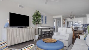 A modern living room with a flat-screen TV, a dining area with a white table and chairs, and a kitchen in the background. - All New! Gulf Front! High End! Pelicans Roost 102 on Sanibel Island (Sanibel)