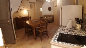 A cozy kitchen with a dining table, wooden chairs, a refrigerator, and a patterned backsplash. - Charming village house (year-round rental) (Montmeyan)