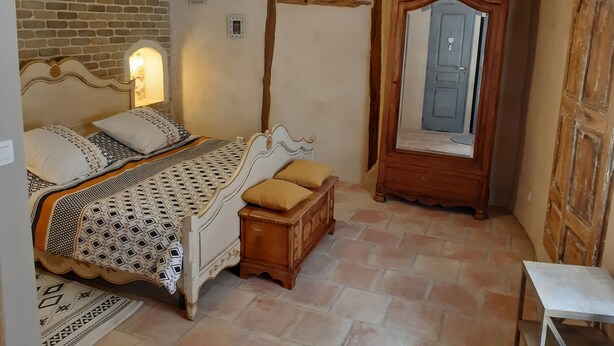 A bedroom with a bed, bedside lamps, a wooden dresser, a mirror, and a small table. - Charming village house (year-round rental) (Montmeyan)