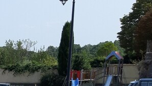 A playground with a slide and climbing structures, surrounded by a fence and trees. - Charming village house (year-round rental) (Montmeyan)
