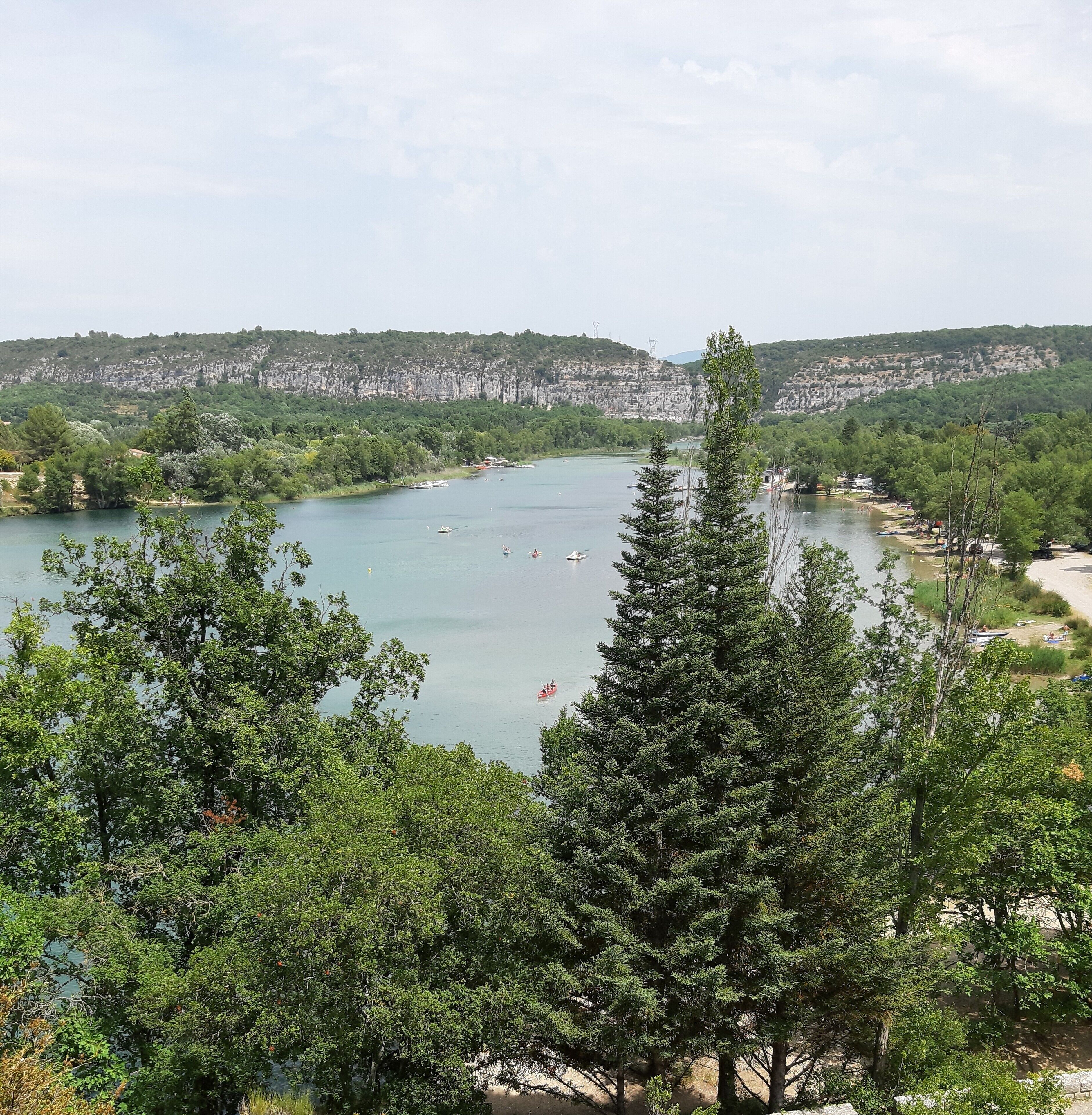 Ein See, umgeben von dichtem Grün und einer fernen, felsigen Klippe.