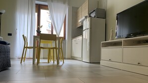 A modern kitchen with a built-in oven, a microwave, and a refrigerator. There is a dining table with chairs and a TV on a stand. - Alleria Holiday Home (Salerno)