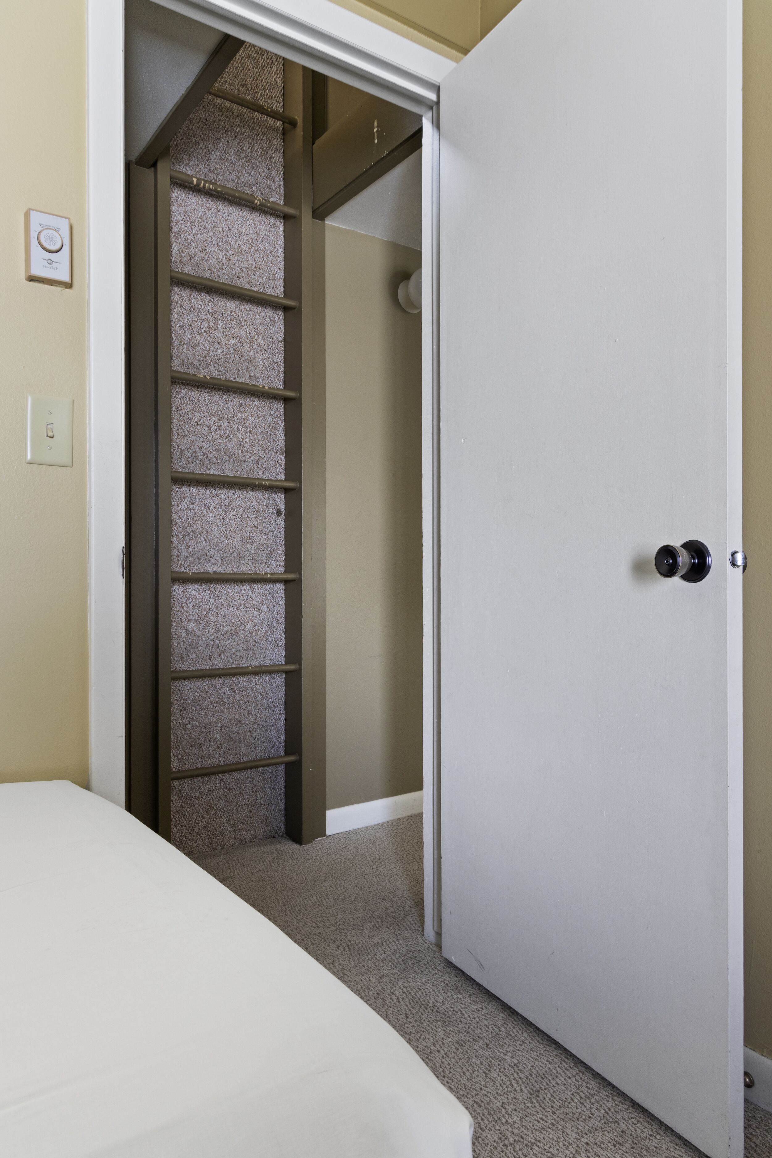 A bedroom with a bed, a white door, and a closet with a striped pattern.