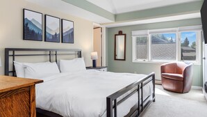 A neatly arranged bedroom with a large bed, a wooden nightstand, a chair, and a window with a view of the outside. - Outpost: Teton Shadows Eagle D - Close to Tetons! (Jackson)