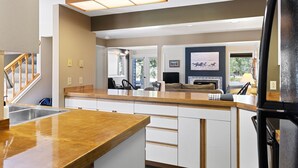 A modern kitchen with a wooden countertop, white cabinets, and a built-in stove. There is a dining area with a table and chairs, and a large window providing natural light. - Outpost: Teton Shadows Eagle D - Close to Tetons! (Jackson)