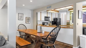 A modern kitchen with white cabinets, a wooden dining table, and black chairs. - Outpost: Teton Shadows Eagle D - Close to Tetons! (Jackson)