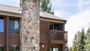 A modern two-story house with a stone chimney, wooden exterior, and a balcony with outdoor seating. - Outpost: Teton Shadows Eagle D - Close to Tetons! (Jackson)