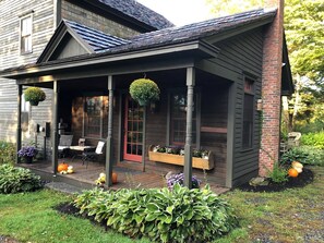 Ein Haus mit Veranda, Essbereich und Garten mit Pflanzen und Kürbissen.
